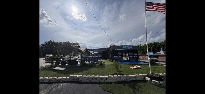 716 Wings and Pizza restaurant exterior — outdoor patio, cornhole, and American flag