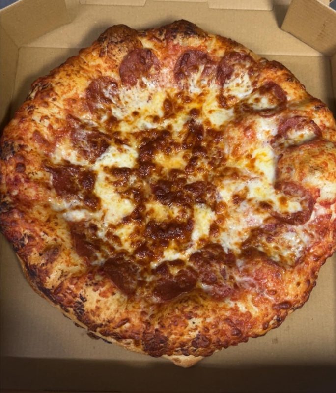 Whole pepperoni pizza fresh from the oven in delivery box